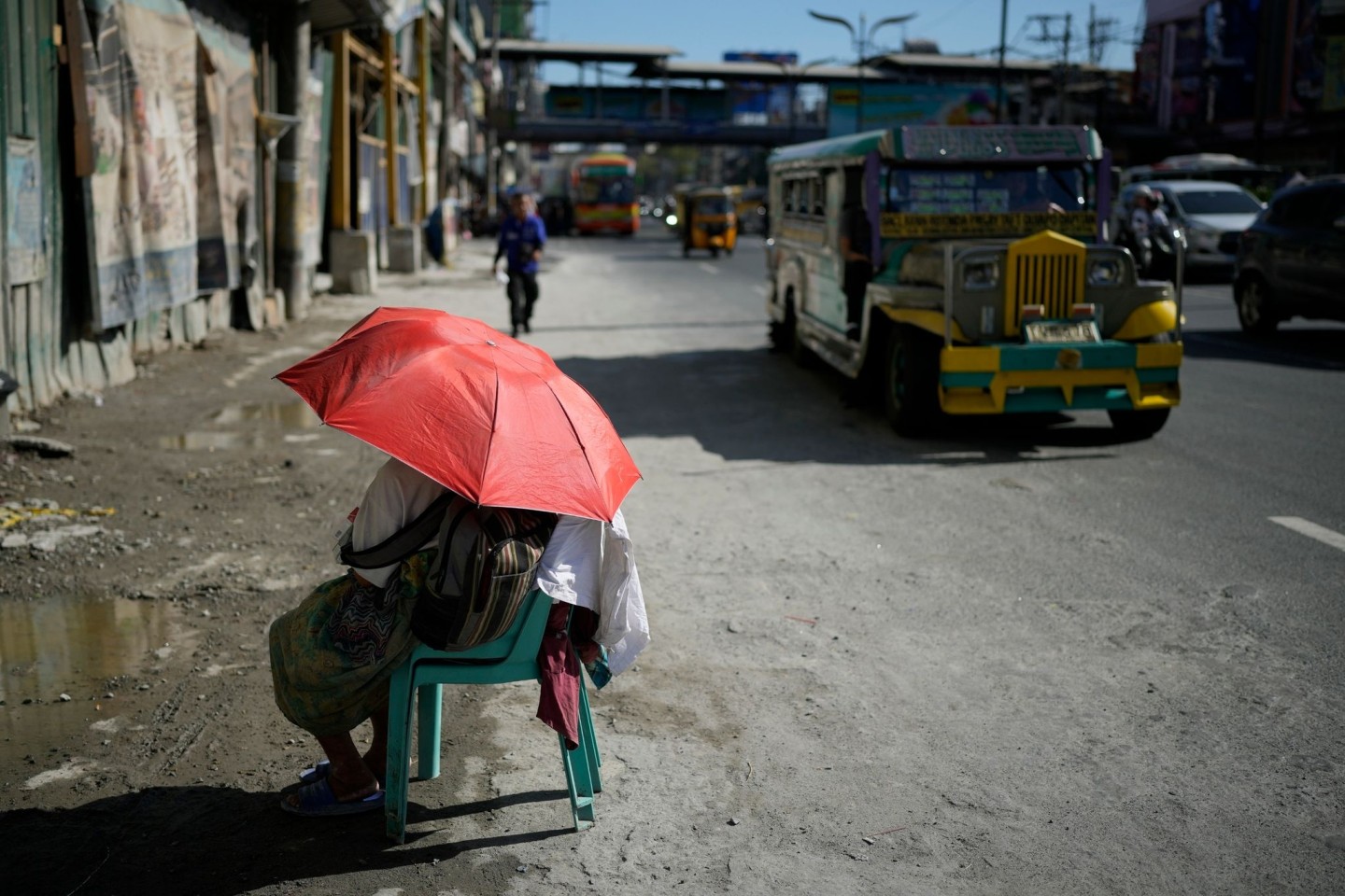 Eine Straßenverkäuferin schützt sich in Manila mit einem Regenschirm vor der Sonne.