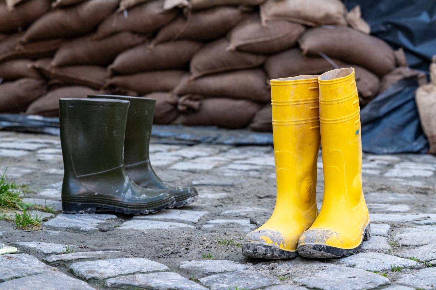 Gummistiefel stehen in der Altstadt vor Sandsäcken. Der Hochwassernachrichtendienst geht von einem baldigen Ende der Hochwasserlage in Bayern aus.