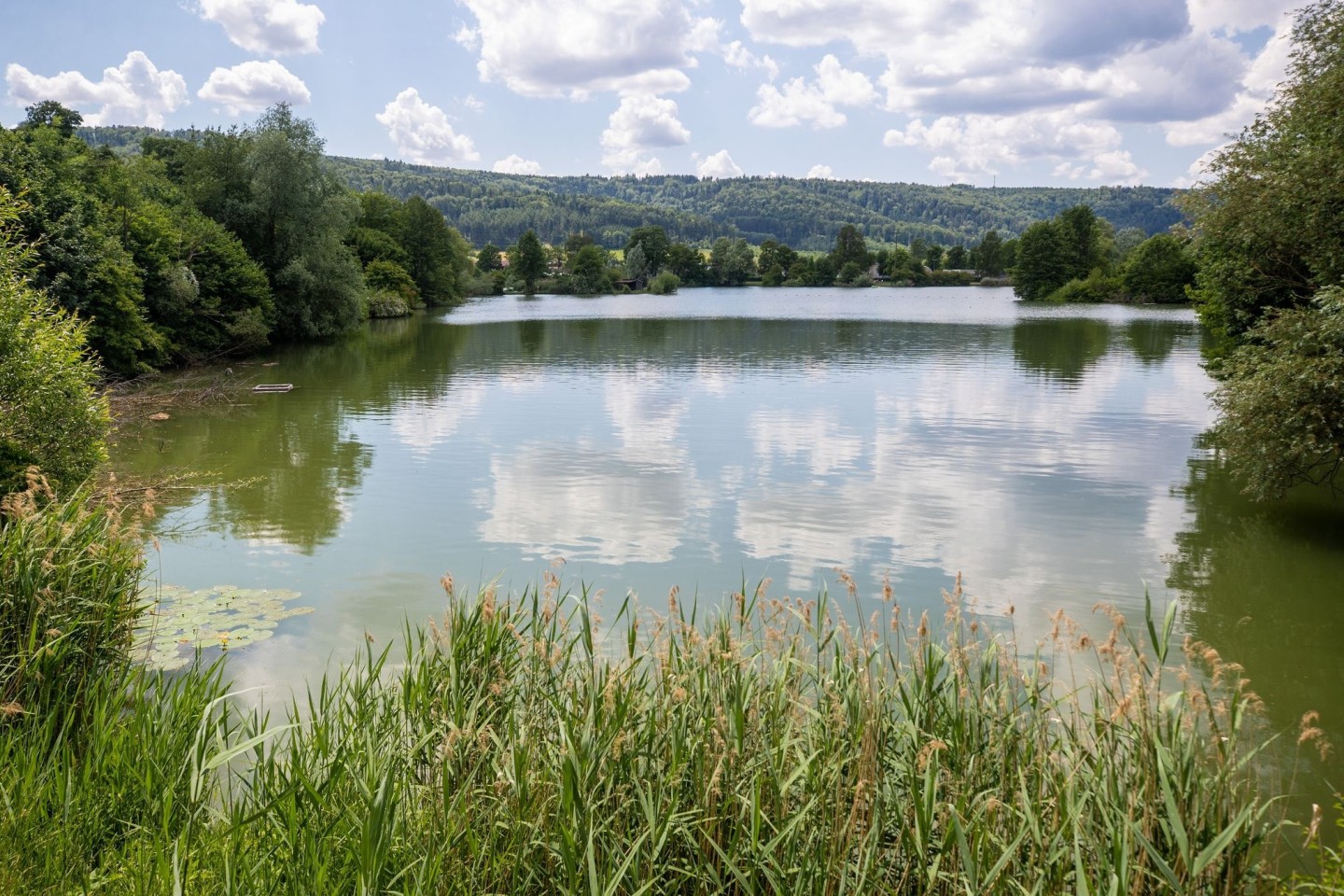 Einzelne Wolken ziehen über einen Badesee hinweg.