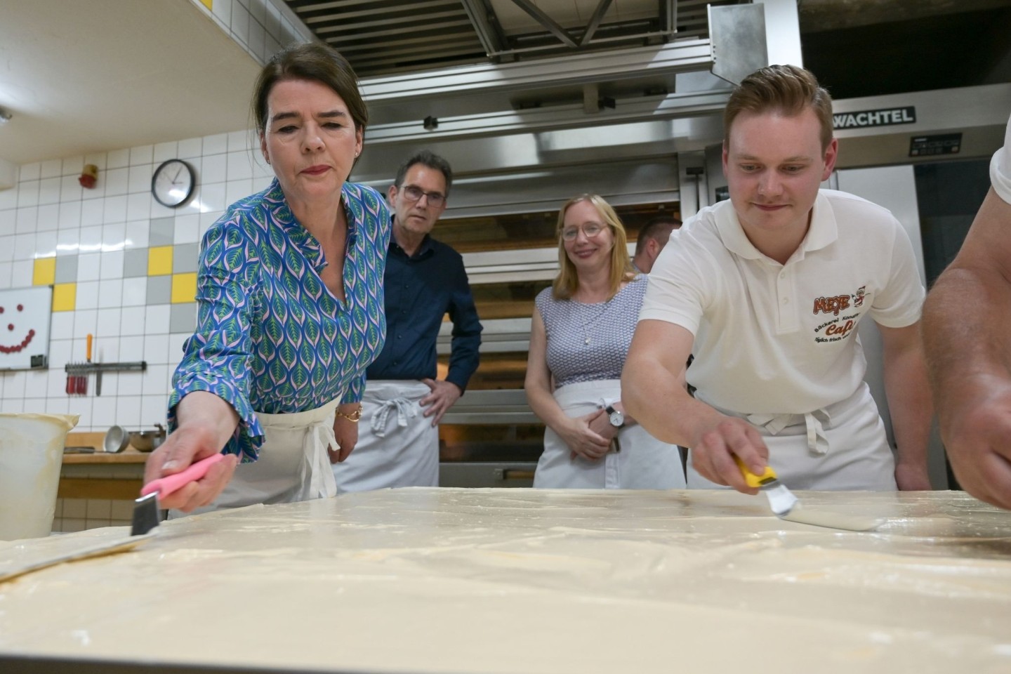 Tagesschau-Sprecherin Susanne Daubner (l) und Bäckermeister Vincent Richter von der Bäckerei Meye verteilen den Sulf-Belag auf dem weltgrößten Mohnkuchen.