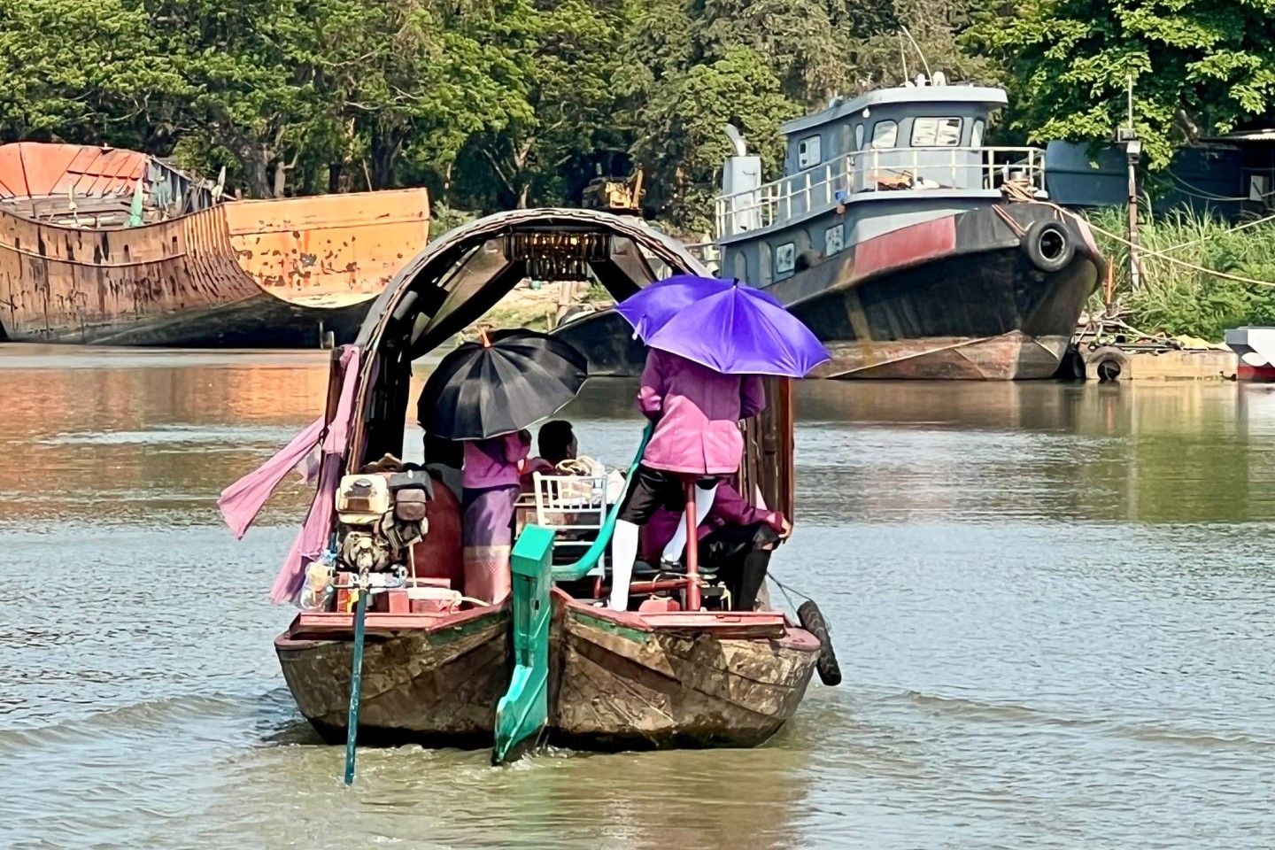 Menschen auf dem Pa Sak River schützen sich mit Sonnenschirmen vor der Sonneneinstrahlung und der extremen Hitze in Thailand.